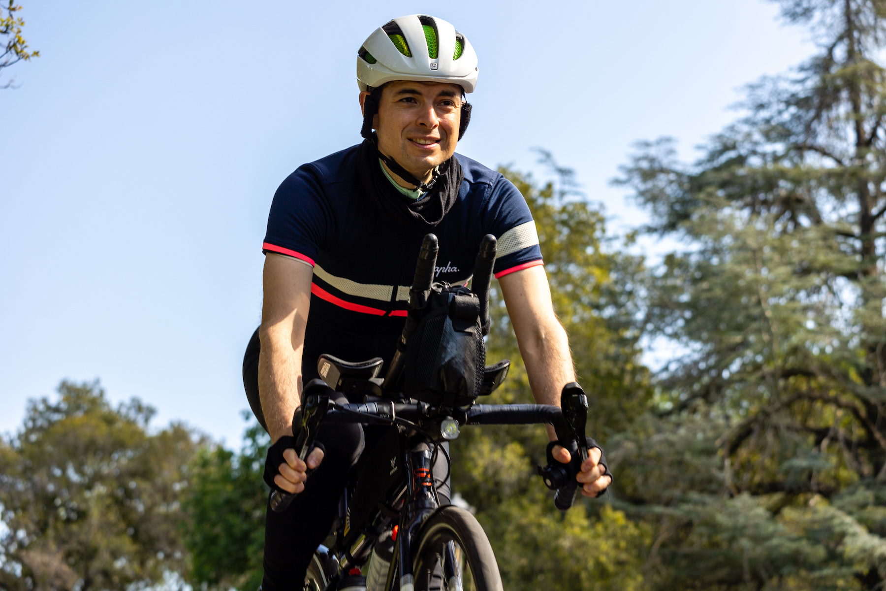 J. Nathan Matias, on a bicycle, with live oak and blue skies in the background and the sun on his face