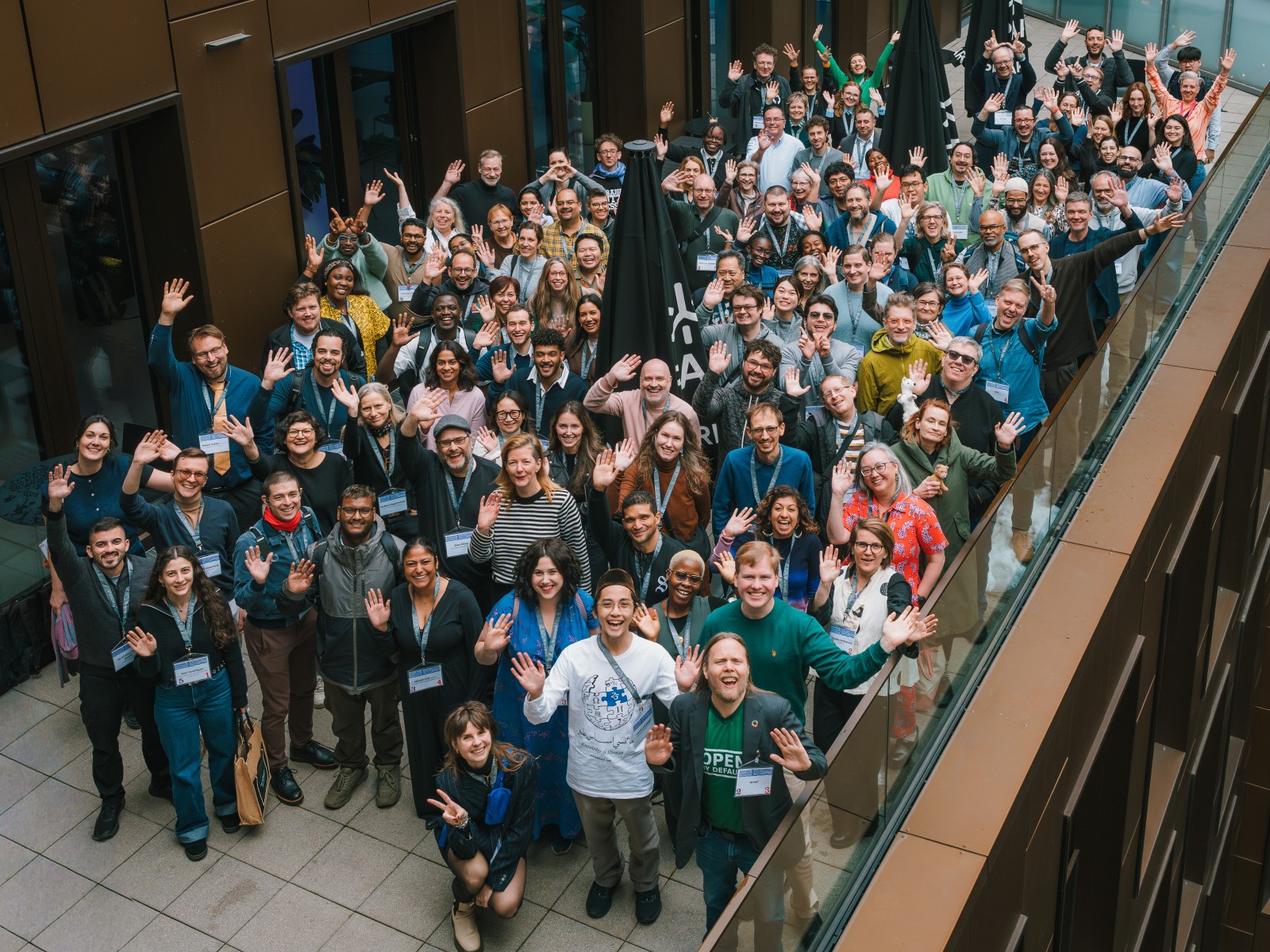 A group of over 50 people at the Wikimedia Futures Lab in Frankfurt smile in front of the camera from a balcony